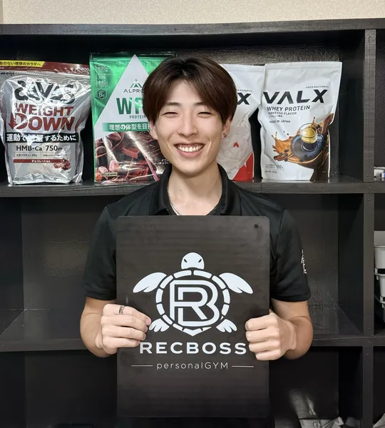 Recbossのロゴボードを持って笑顔で立つ副代表トレーナー 土生大貴（Daiki）